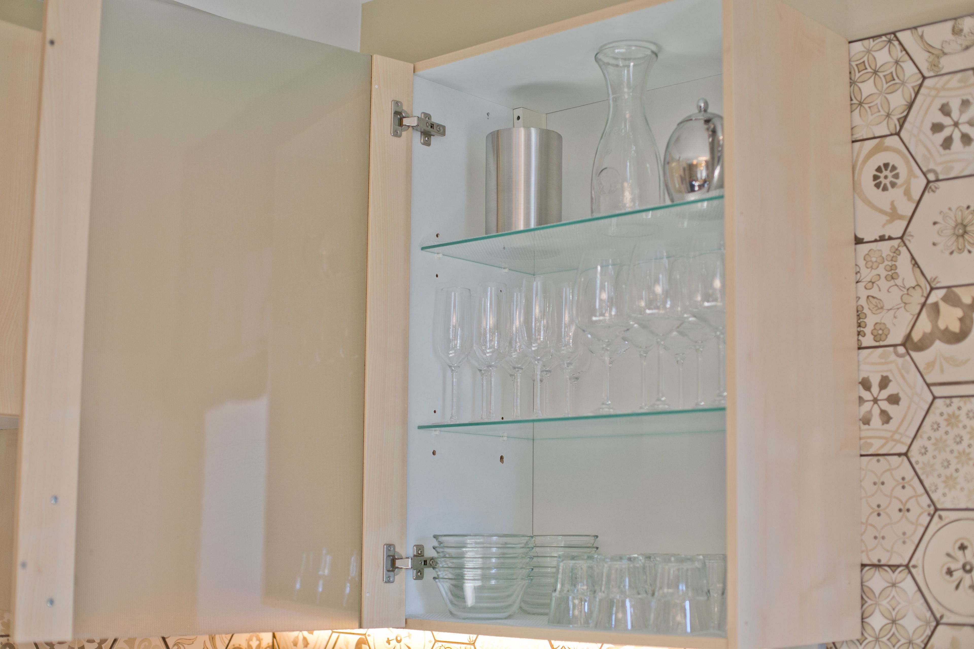 A cabinet with multiple shelves containing glassware and dishes.