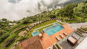 Un área de piscina con una terraza de madera, sillas de descanso y un jacuzzi.