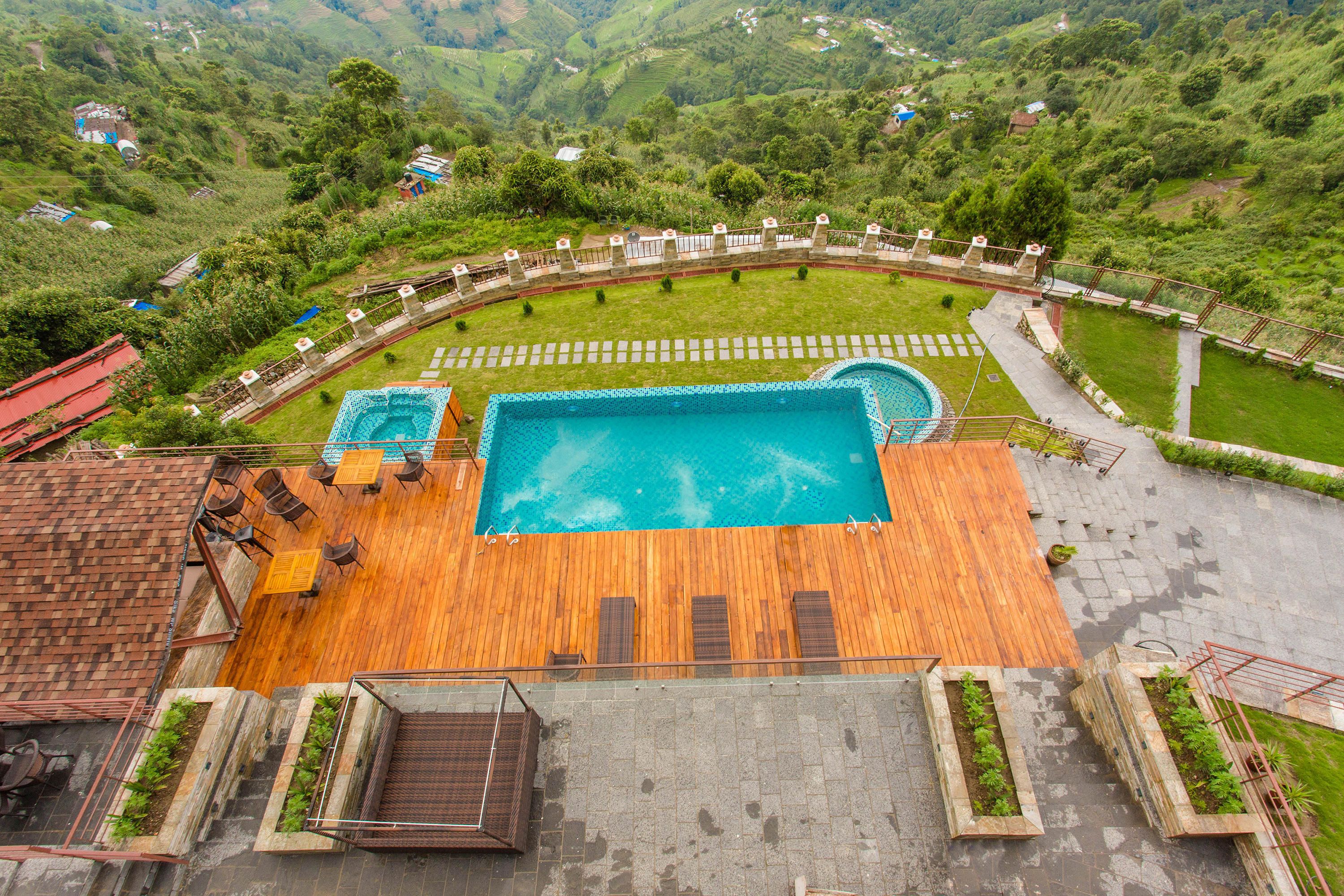 Un área de piscina en la azotea con terraza de madera, sillas de descanso y piscina.