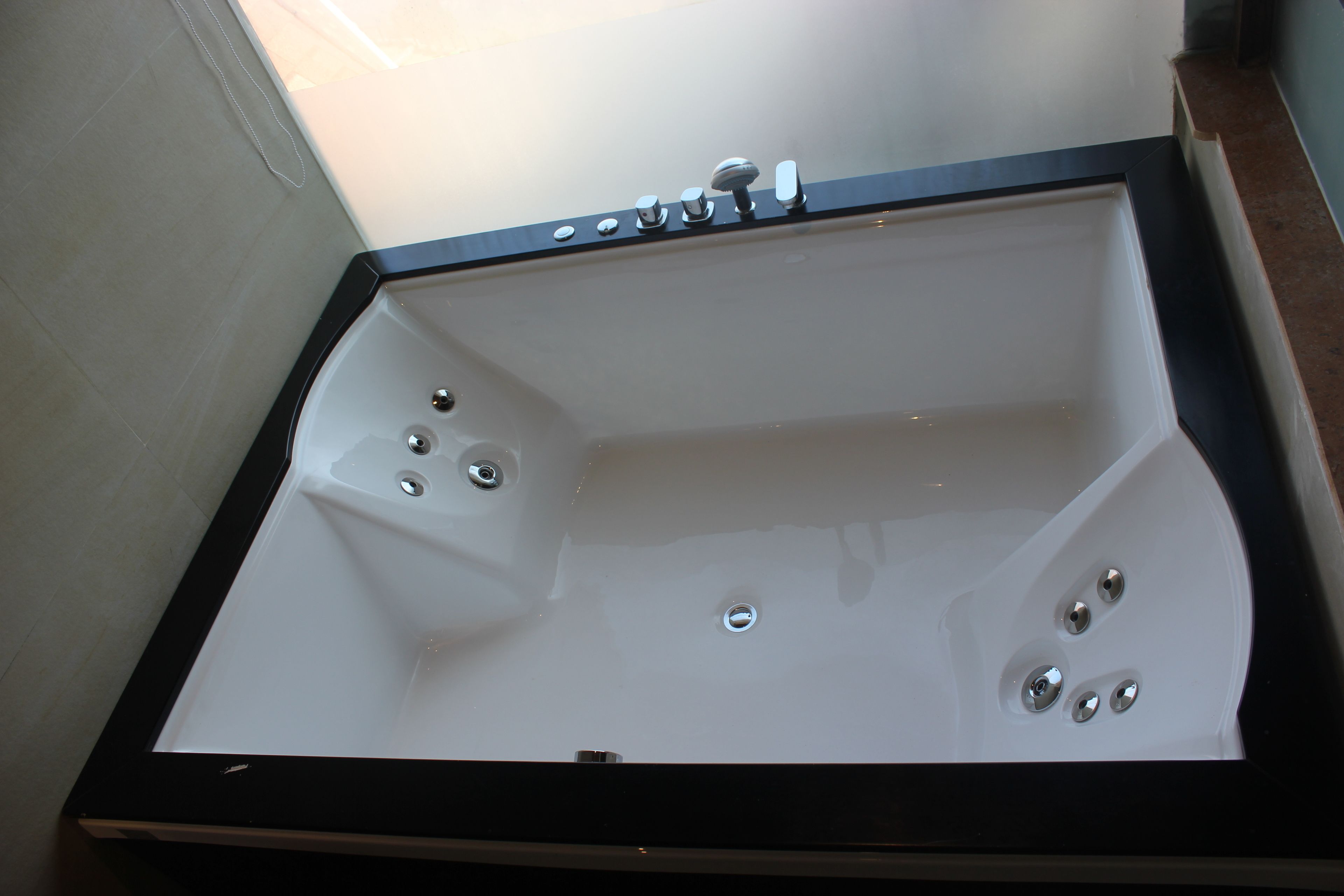 A bathtub with multiple faucets and a drain.