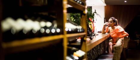 A woman sitting at a bar with a wine rack in the background.