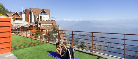 A person exercising on a purple mat with a mountain view in the background.
