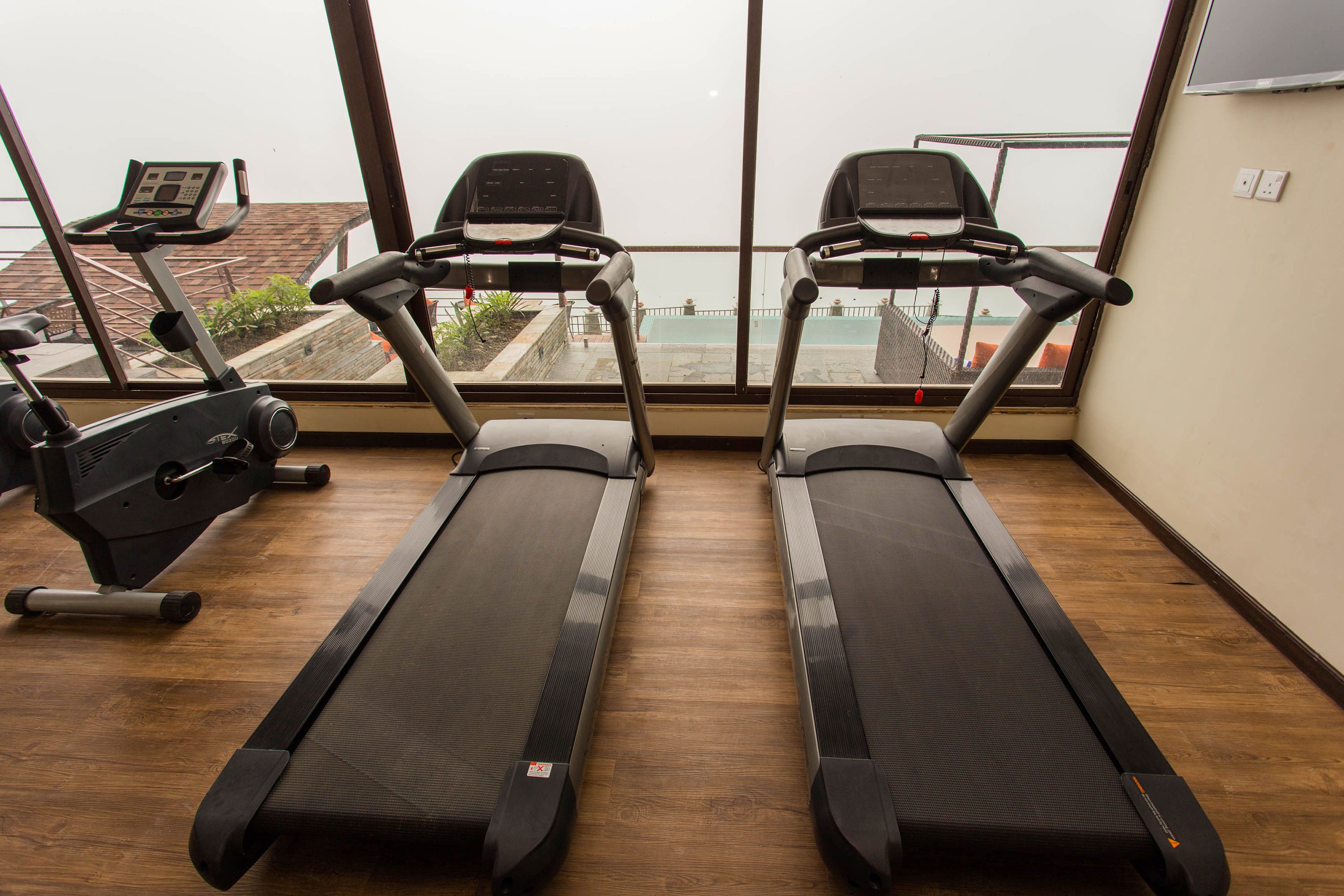 A gym with two treadmills in the foreground and an elliptical machine in the background.