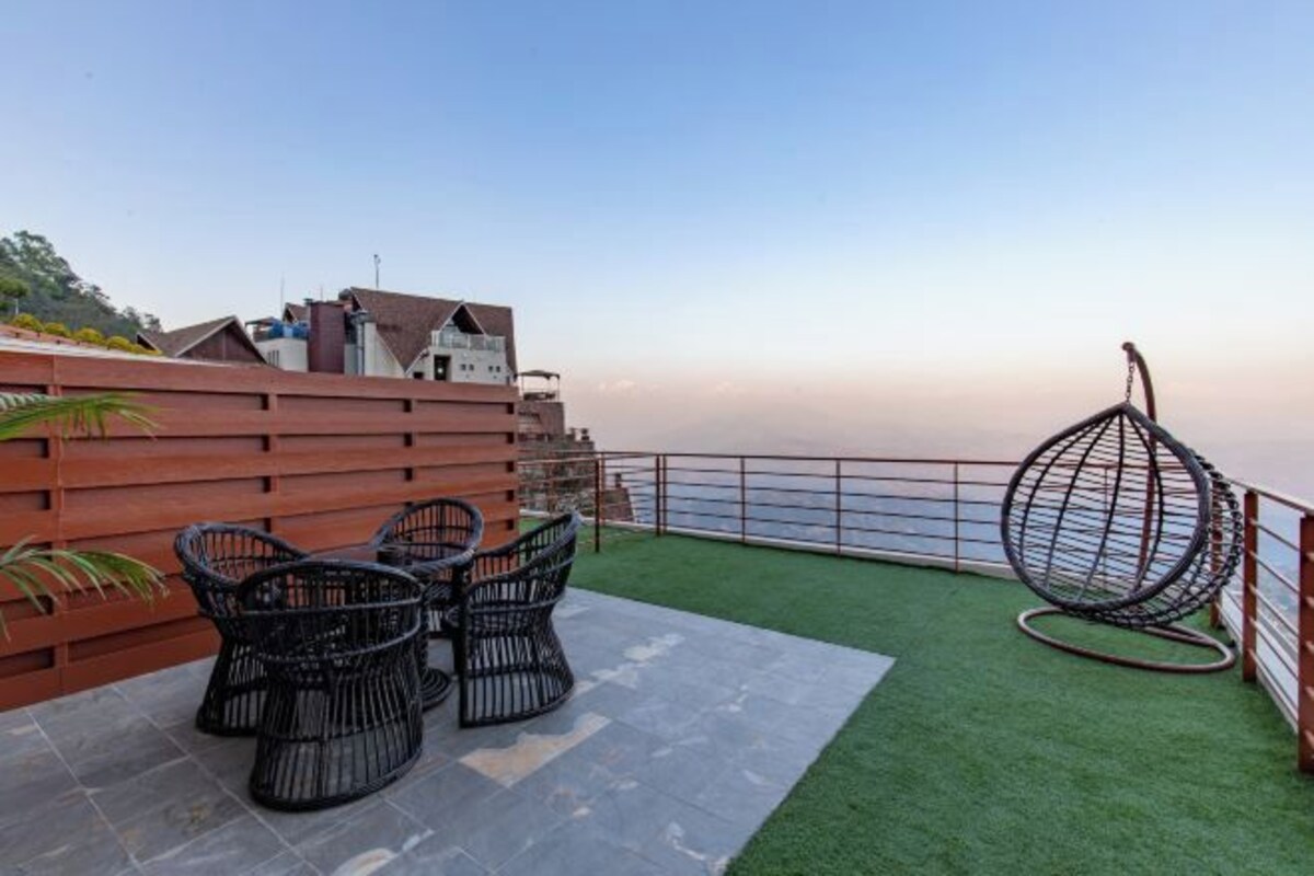 Una terraza en la azotea con vistas al mar, que cuenta con una valla de madera, una silla colgante y una mesa con sillas.