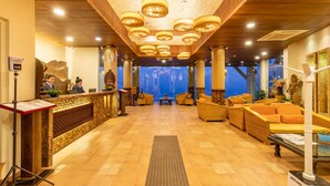 Un vestíbulo de hotel con una mesa de recepción, una zona de estar y vistas del propio vestíbulo al fondo.