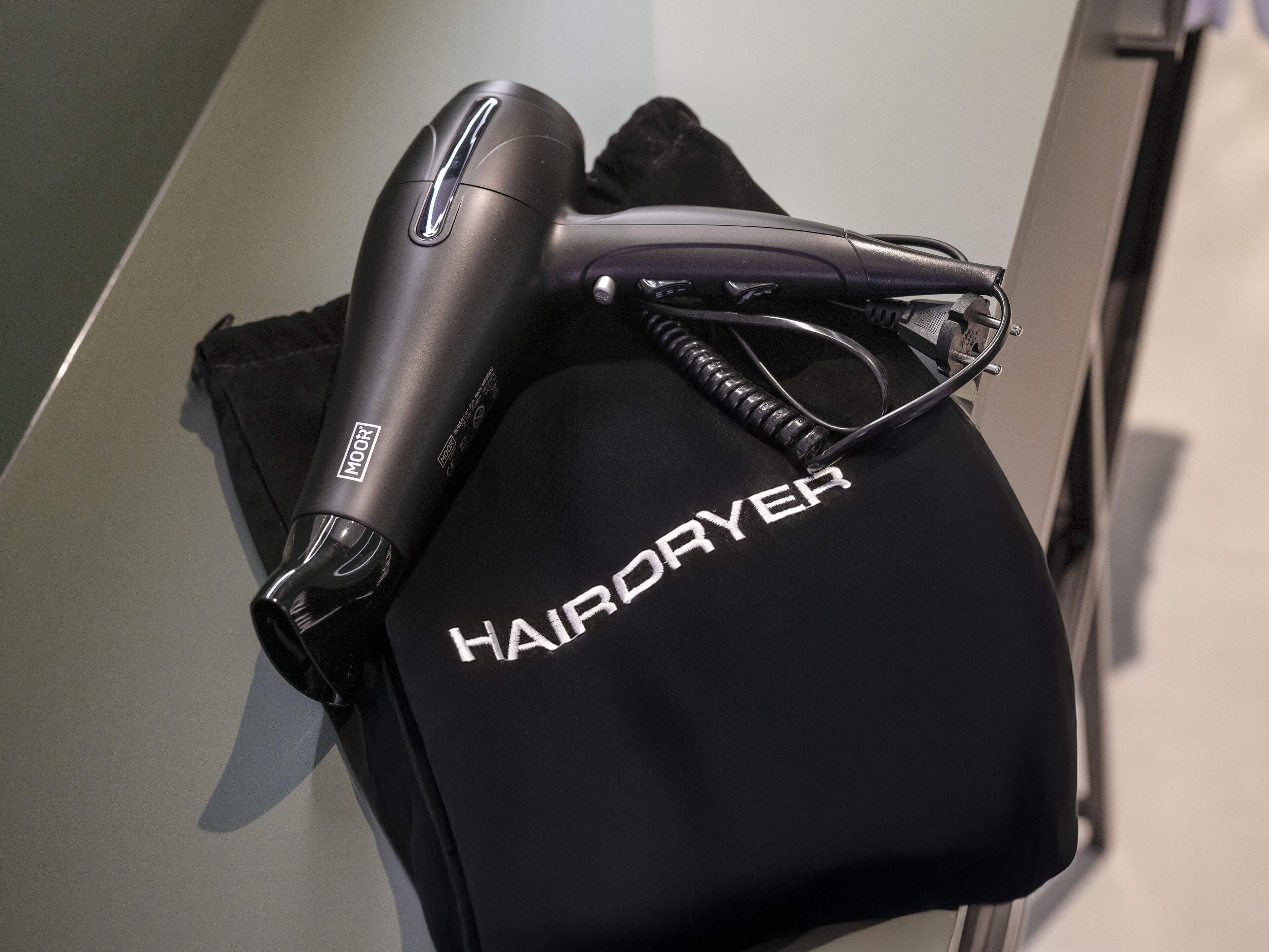 A hairdryer and a black bag with the word "HAIRDRYER" on it.