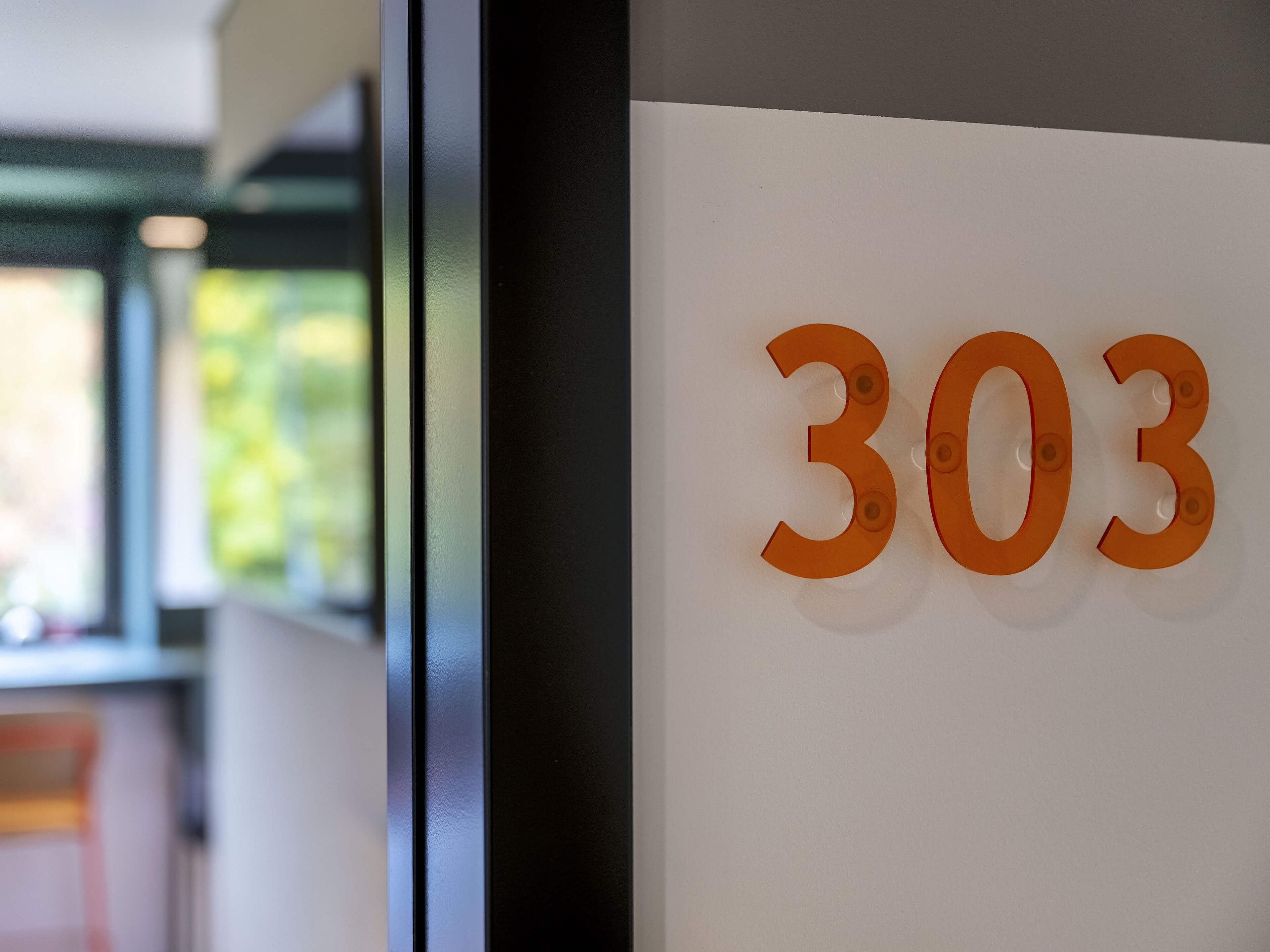 En væg med nummer 303 i orange bogstaver.