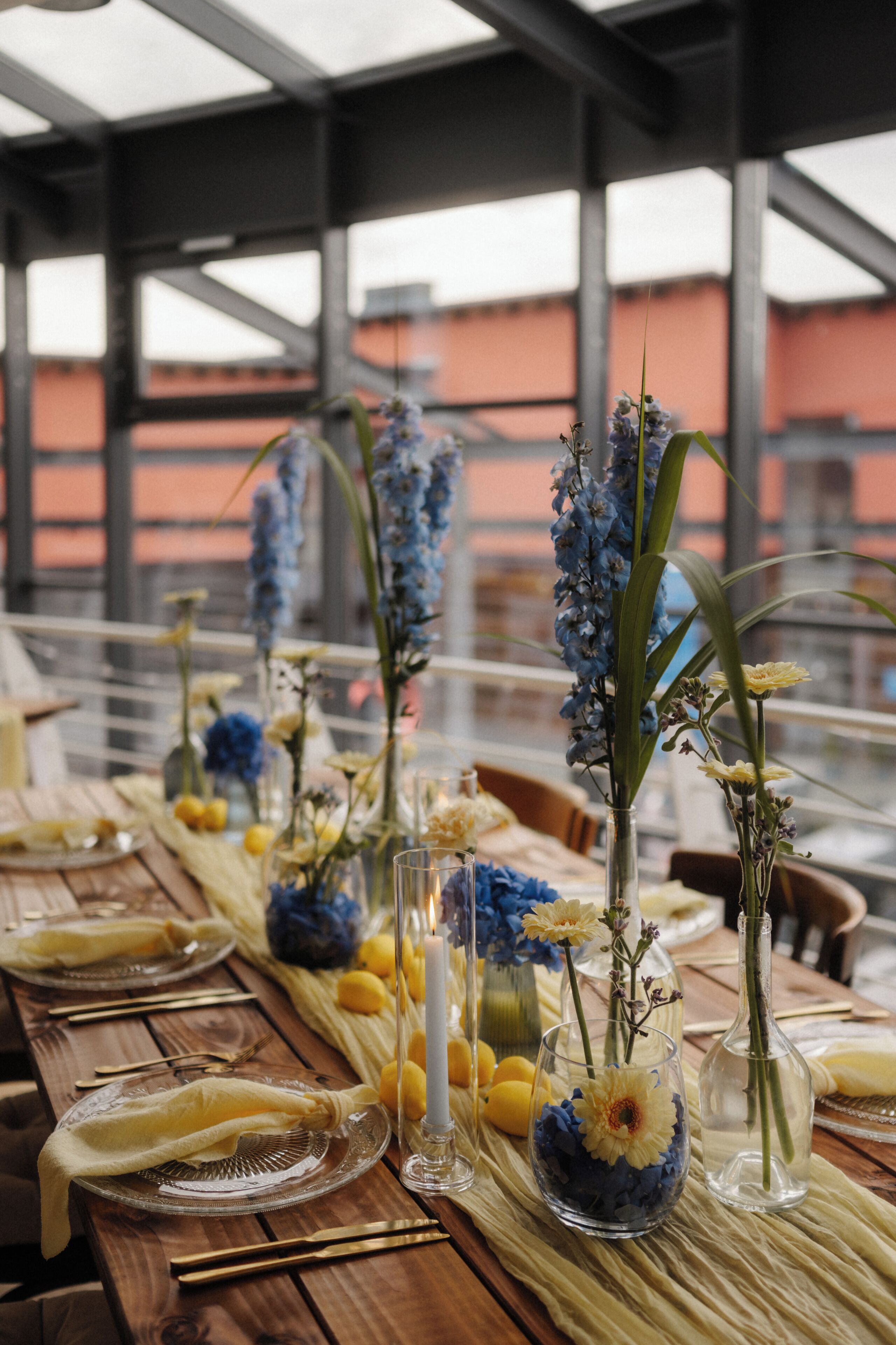 A dining table set with clear glass plates, cutlery, and vases with flowers.