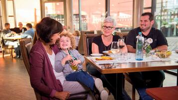 Una famiglia cena in un ristorante con vista sulla città attraverso ampie finestre.