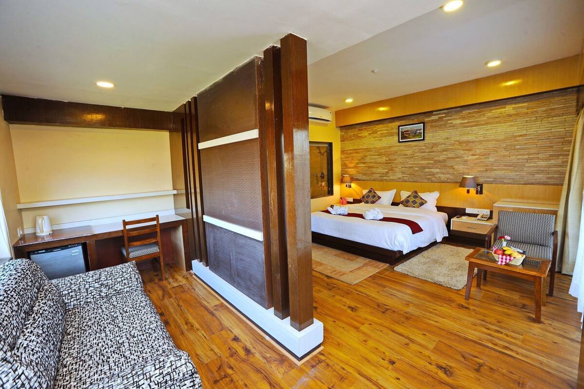 A hotel room with a bed, desk, chair, and a small table with a basket.