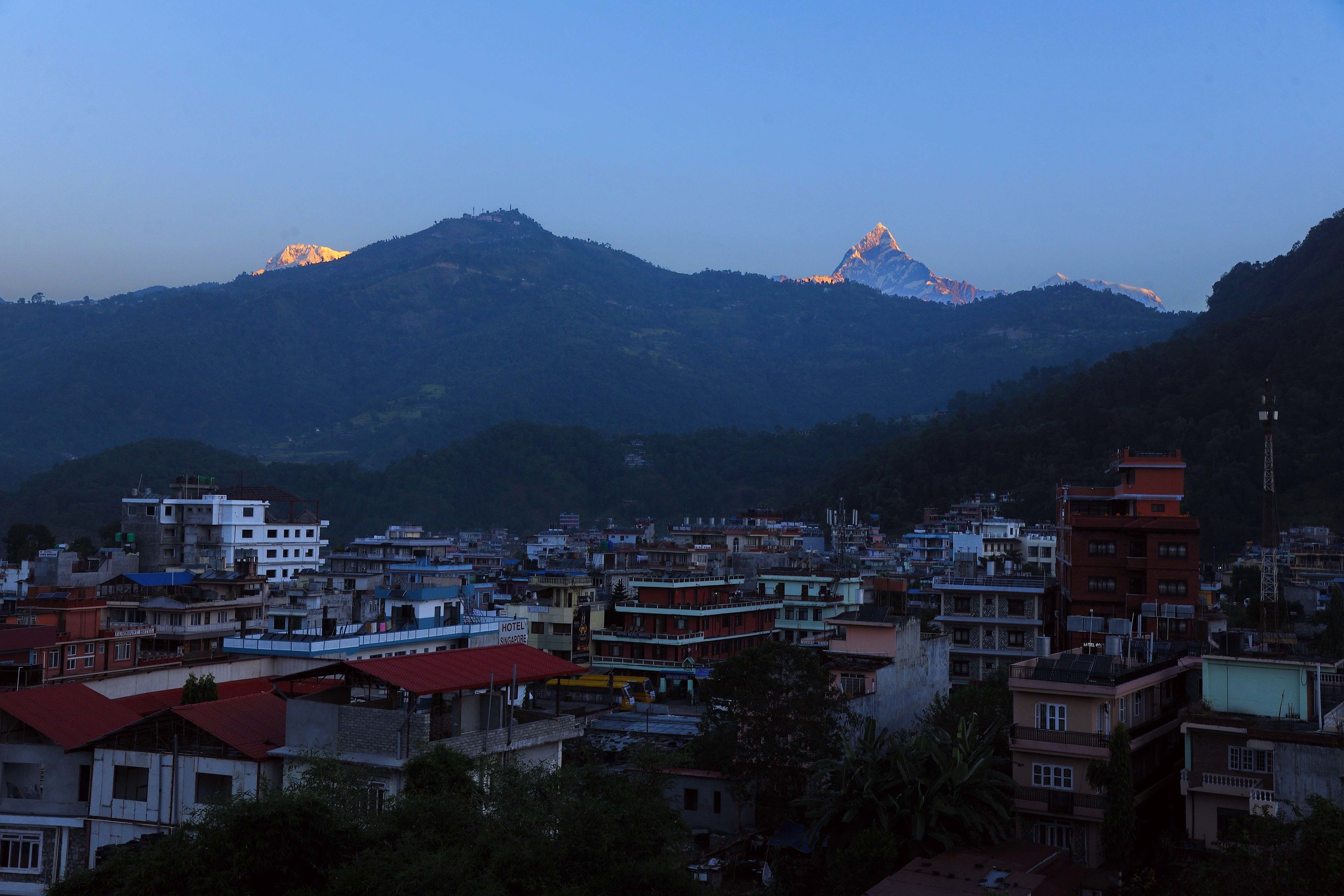 A cityscape with a prominent mountain range in the background.