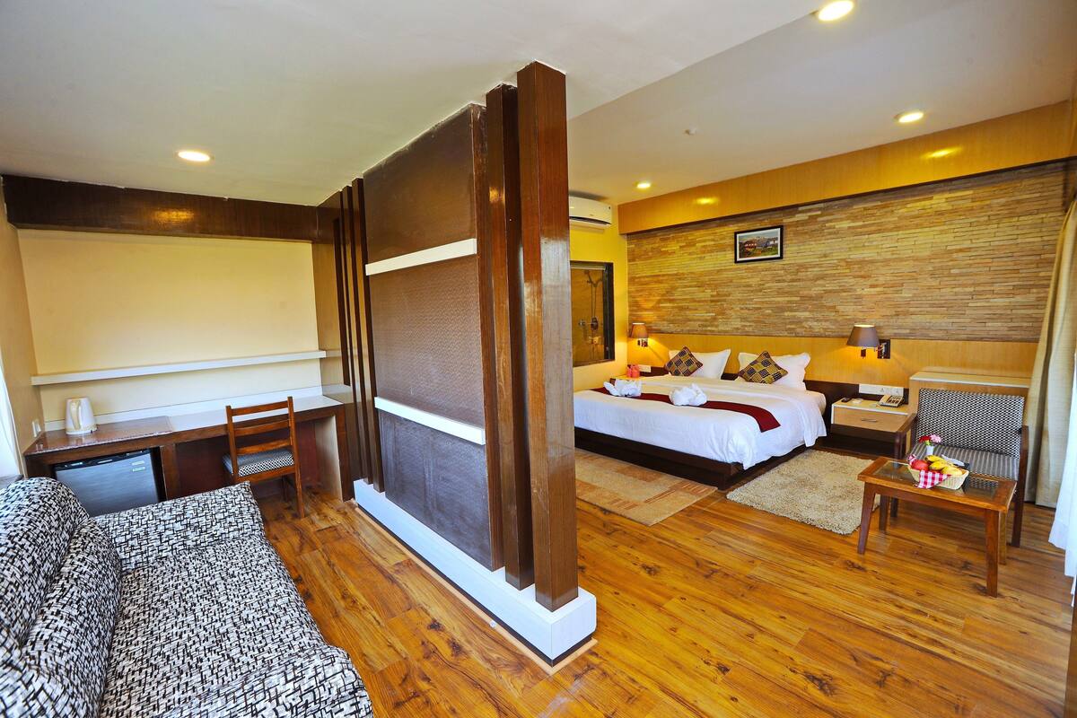 A hotel room with a bed, desk, chair, and a small table with a basket.