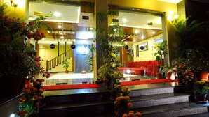 A hotel lobby with a staircase, potted plants, and a red carpet. - Hotel Queens Park (Pokhara)
