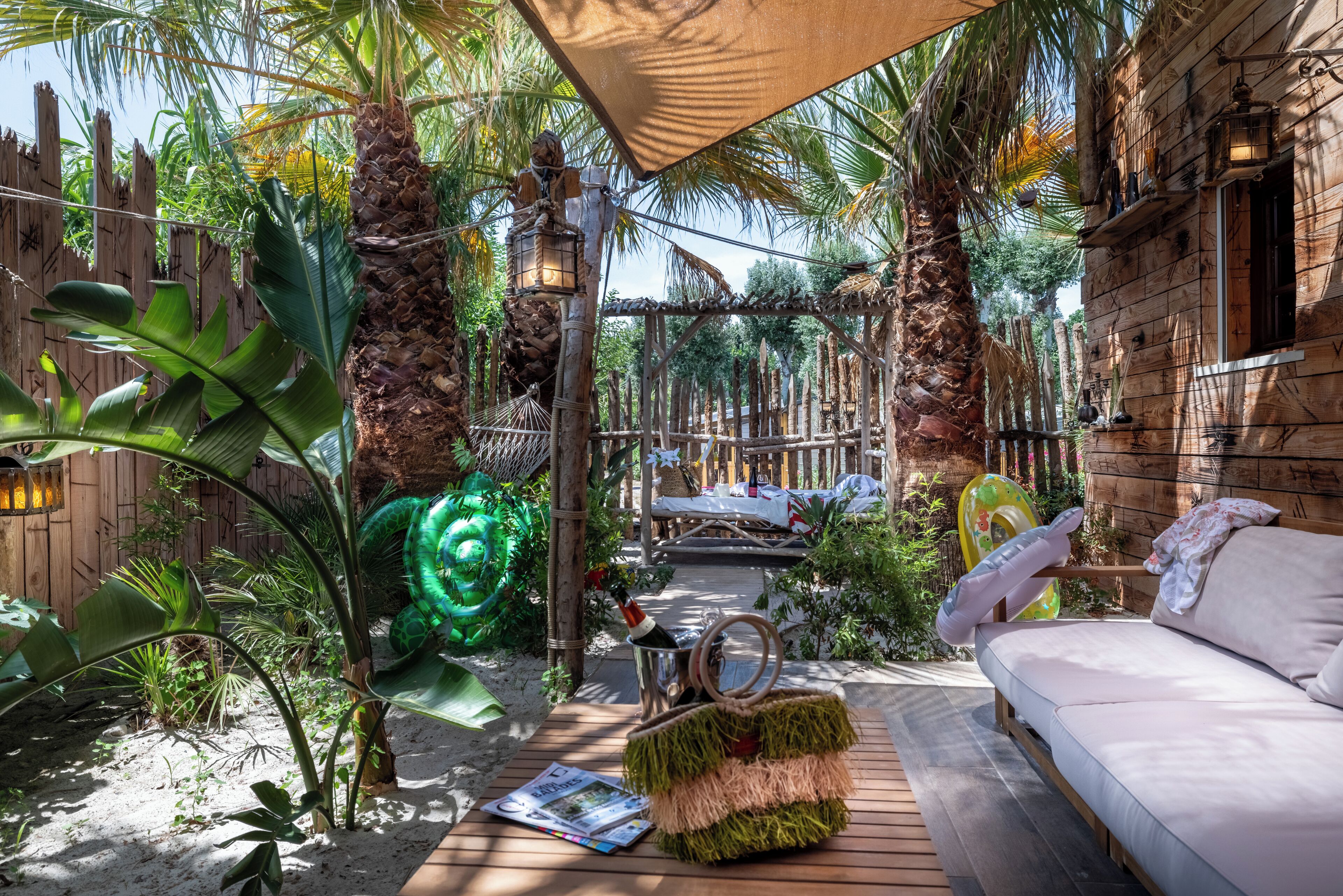 A wooden deck with a sofa, a hammock, and a tiki-style lamp.