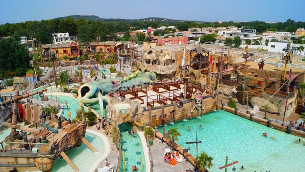 Een waterpark met een groot zwembad, glijbanen en diverse speelattracties.