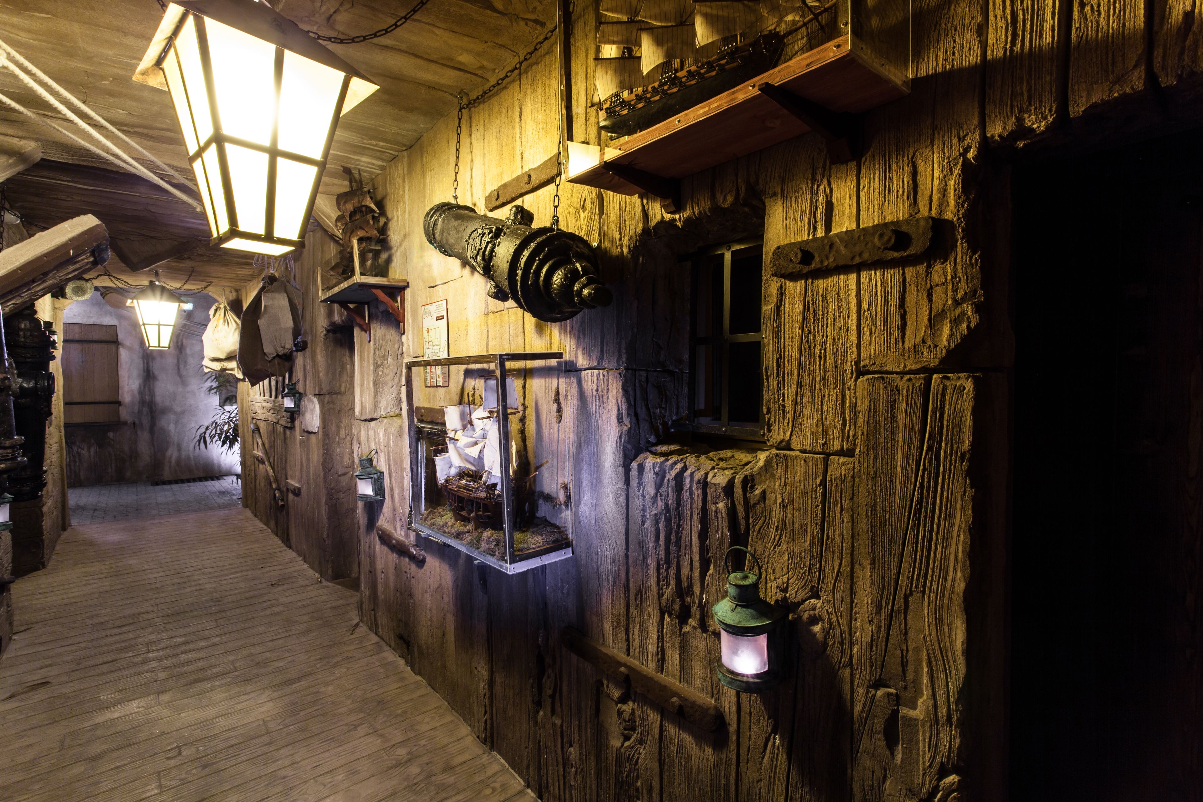 Un intérieur en bois, avec un plancher en bois, une lanterne et une maquette de bateau.
