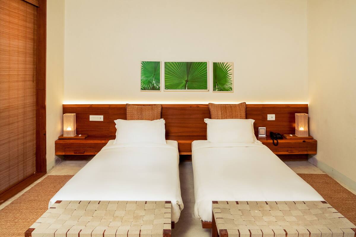 A hotel room with a double bed, two bedside tables, a nightstand, a lamp, and a wall-mounted power outlet.