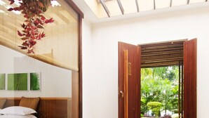 A room with a bed, a small table, and a window overlooking a garden. - Kasara Resort - Chitwan National Park (Bharatpur)