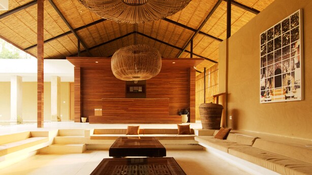 A spacious lobby with a high ceiling, a large woven light fixture, and a seating area with sofas and a coffee table. - Kasara Resort - Chitwan National Park (Bharatpur)