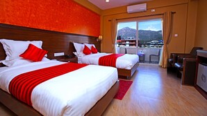 A hotel room with two beds, a red and white color scheme, a view of mountains, and a balcony with seating. - Hotel Iceland (Pokhara)