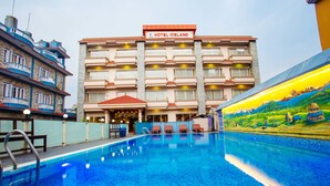 A hotel with a swimming pool, a sign reading "HOTEL ICELAND", and a mural of a landscape on the adjacent wall. - Hotel Iceland (Pokhara)
