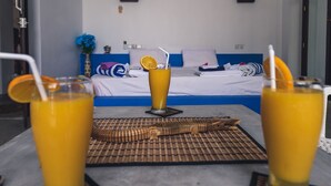 Una habitación con una cama, dos vasos de jugo de naranja y una mesa con un mantel individual.