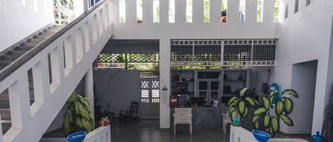 A spacious indoor area with a high ceiling, a central decorative rug, and a staircase leading to an upper level.