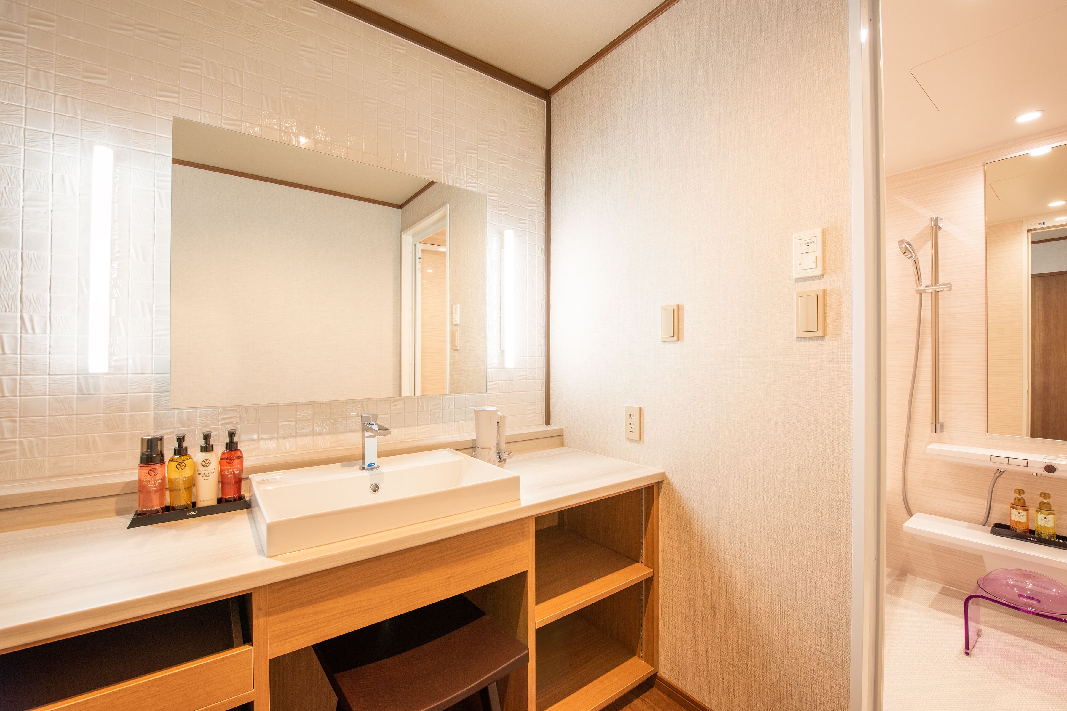 Une salle de bain moderne avec un grand miroir, deux lavabos, des étagères en bois et un espace douche.