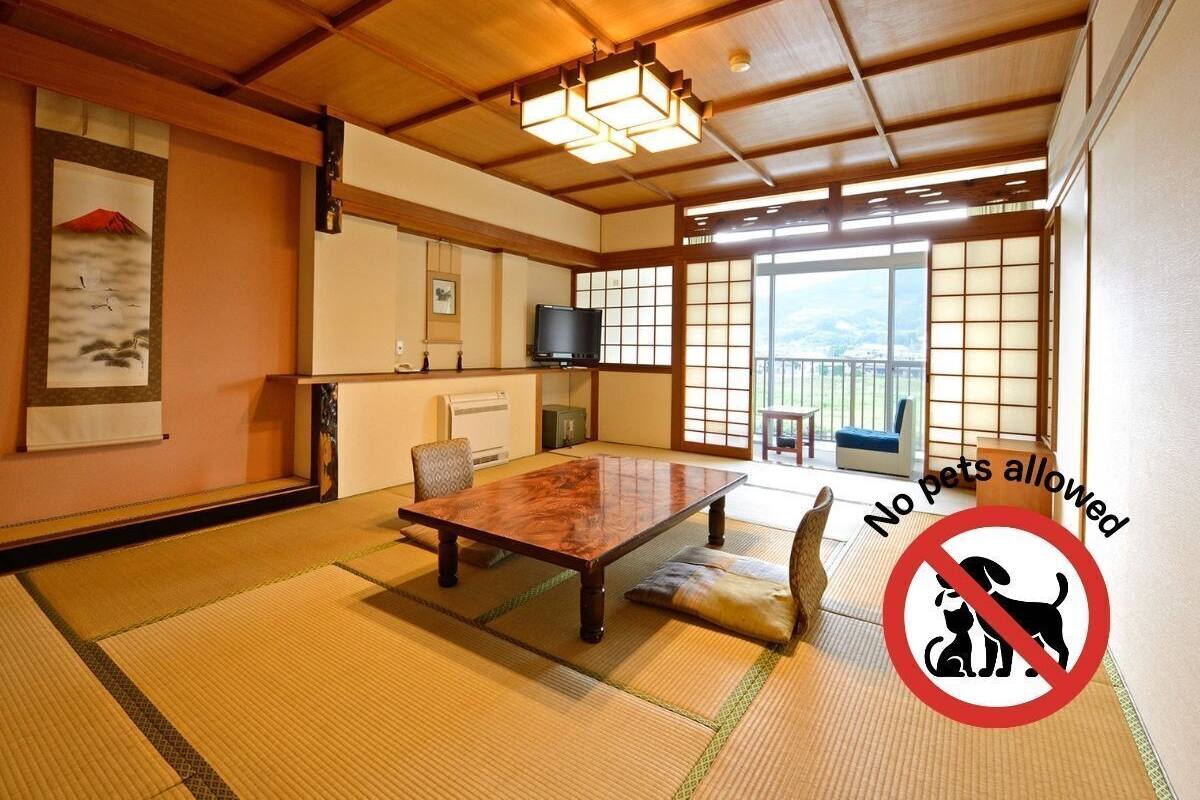 Une pièce de style japonais traditionnel, avec un sol recouvert de tatamis, une table en bois et des portes coulissantes.