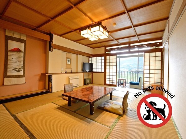 Une pièce de style japonais traditionnel, avec un sol recouvert de tatamis, une table en bois et des portes coulissantes.