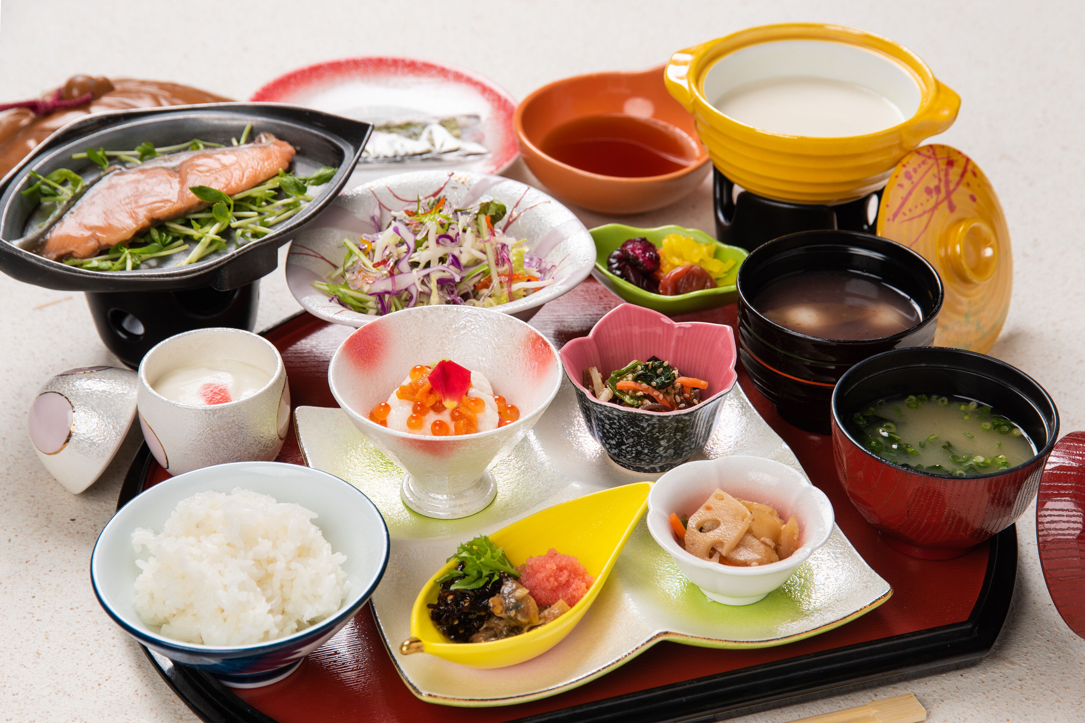 A variety of dishes including rice, salmon, and soup, arranged on a tray.