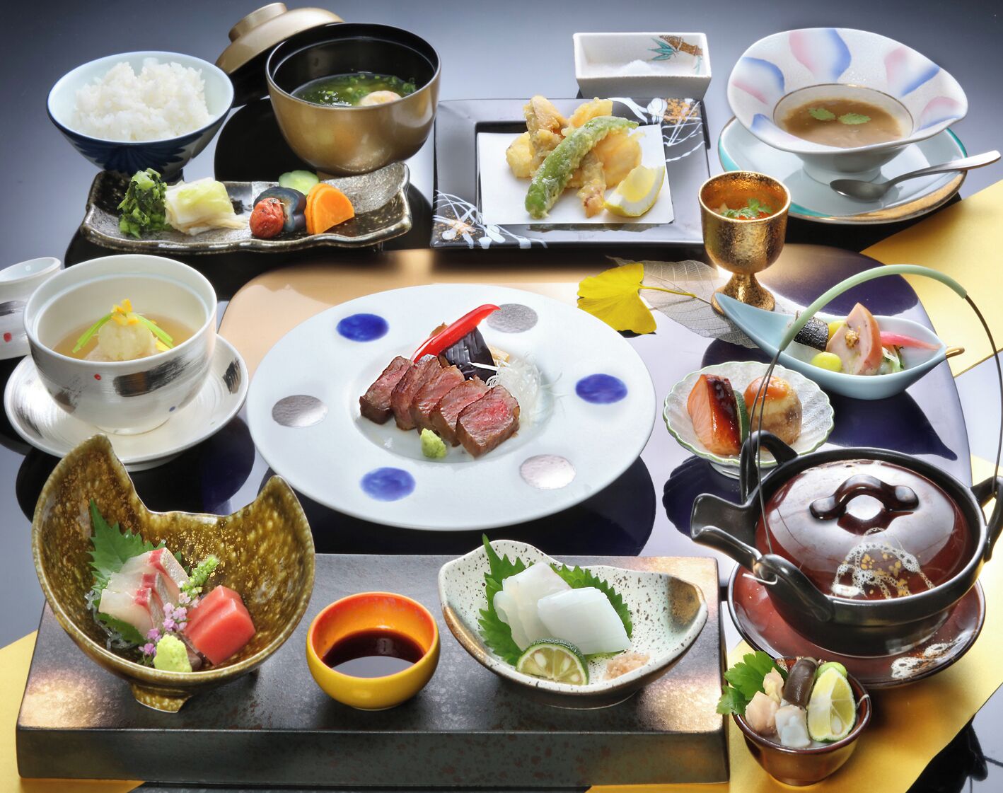 A variety of Japanese dishes arranged on a table, including sushi, sashimi, and bowls of soup.