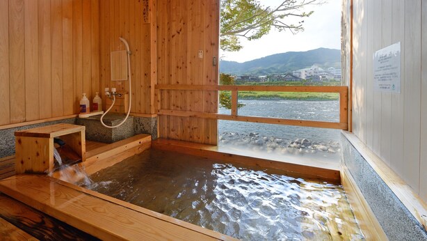 Eine traditionelle Holzbadewanne mit Blick auf einen Fluss und Berge.