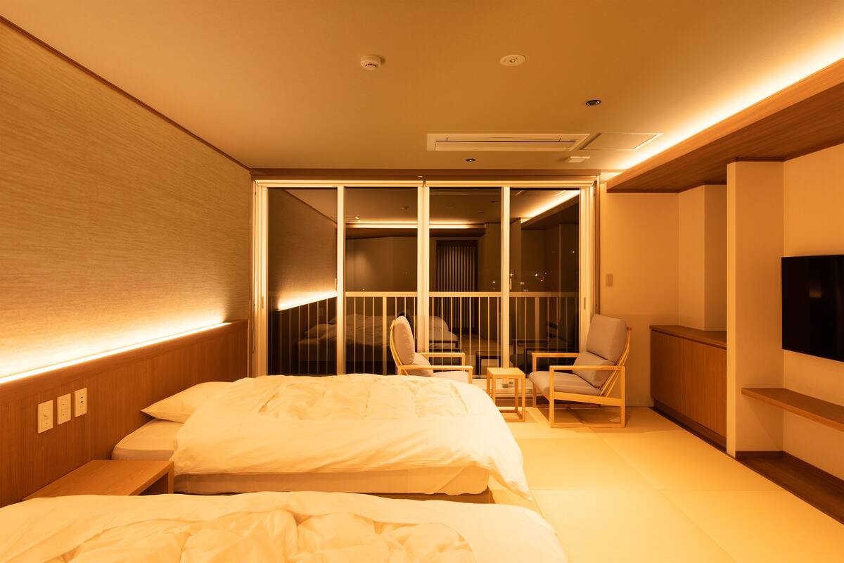 Une chambre d’hôtel avec un lit, deux chaises, une petite table et un téléviseur.