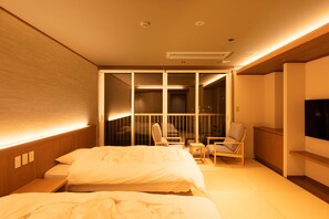 Une chambre d’hôtel avec un lit, deux chaises, une petite table et un téléviseur.
