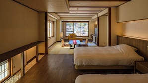 Habitación de hotel con dos camas, un sofá, una mesita y vistas al exterior.