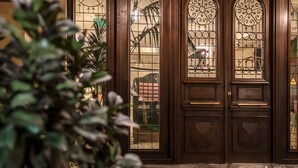 A hotel entrance with a dark wooden door, a glass panel with a grid pattern, and a marble floor. - Museum Hotel Orbeliani (Tbilisi)