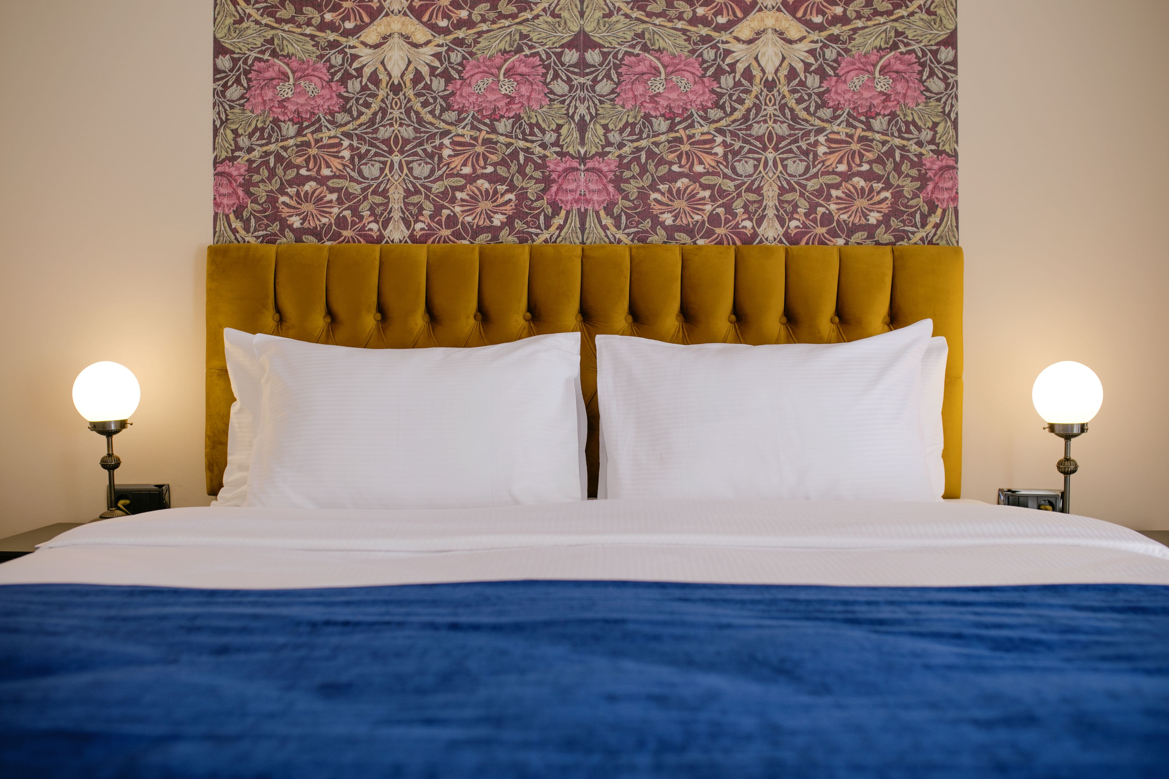 A bed with a tufted headboard, white bedding, and two bedside lamps.