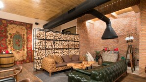 A cozy living room with a fireplace, a green leather sofa, a brown tufted sofa, and a wooden coffee table. - Museum Hotel Orbeliani (Tbilisi)