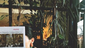 A person reading a newspaper at a table with a dessert and coffee. - Museum Hotel Orbeliani (Tbilisi)