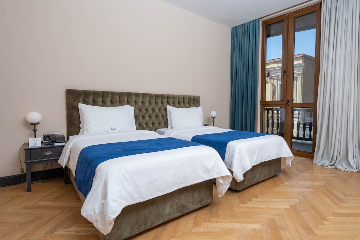 Habitación de hotel con dos camas, una mesita de noche, un teléfono y vistas al exterior a través de un ventanal grande.