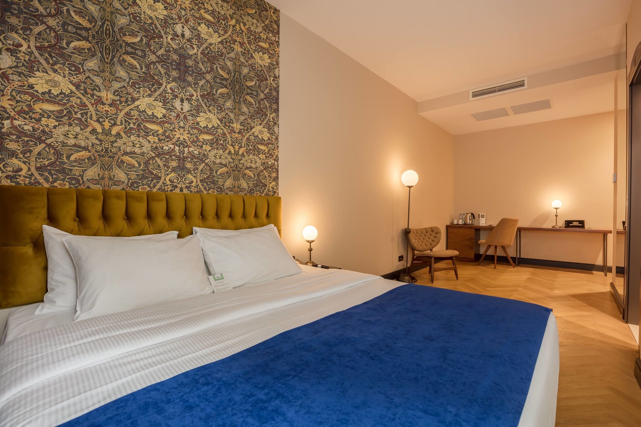 A hotel room with a large bed, a desk, and a chair.