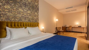 A hotel room with a large bed, a desk, and a chair.
