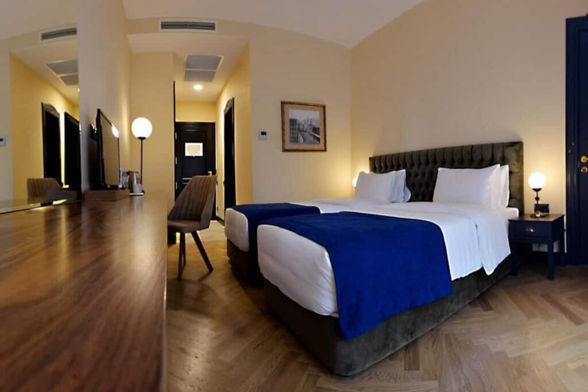 Una habitación de hotel con una cama grande, una silla, un escritorio y una lámpara.