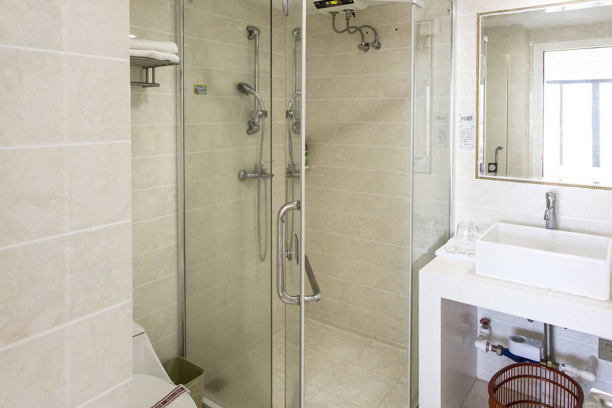 A modern bathroom with a glass-enclosed shower, a white sink, and a mirror above it.