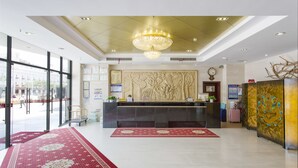 A hotel lobby with a reception desk, a chandelier, a large window, and a red carpet. - Sanya Huabaoshi Hotel (Sanya)