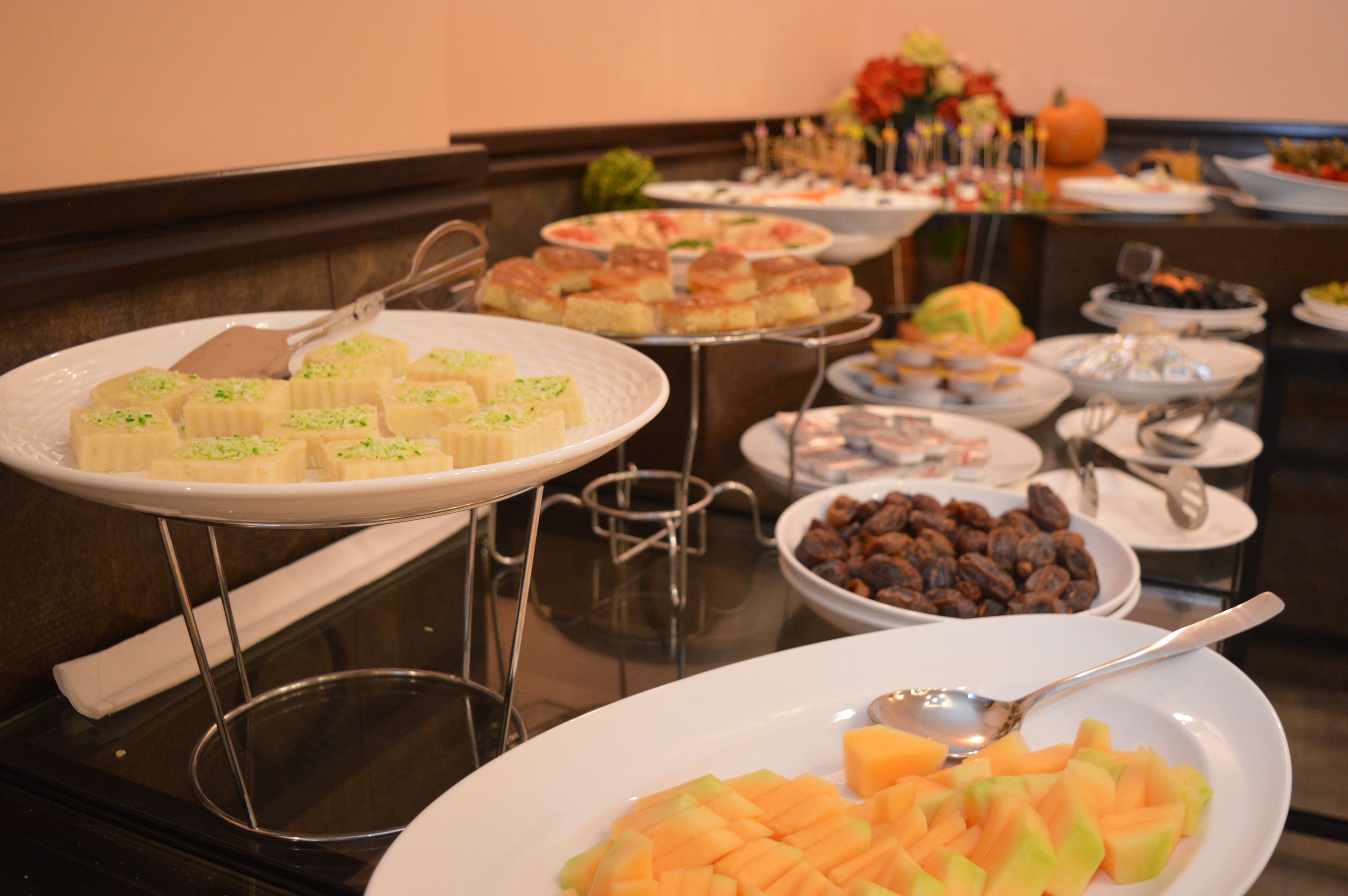 A buffet with various dishes including pastries, fruits, and nuts.