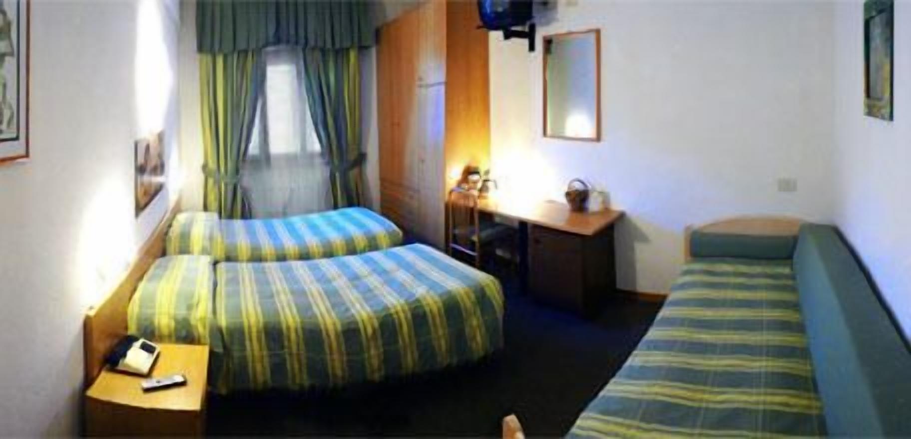 Een kleine, praktische kamer met twee bedden, een bureau en een stoel.
