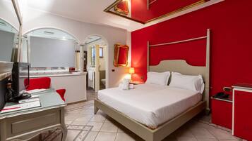Une chambre d’hôtel avec un lit, un bureau et un mur d’accent de couleur rouge.