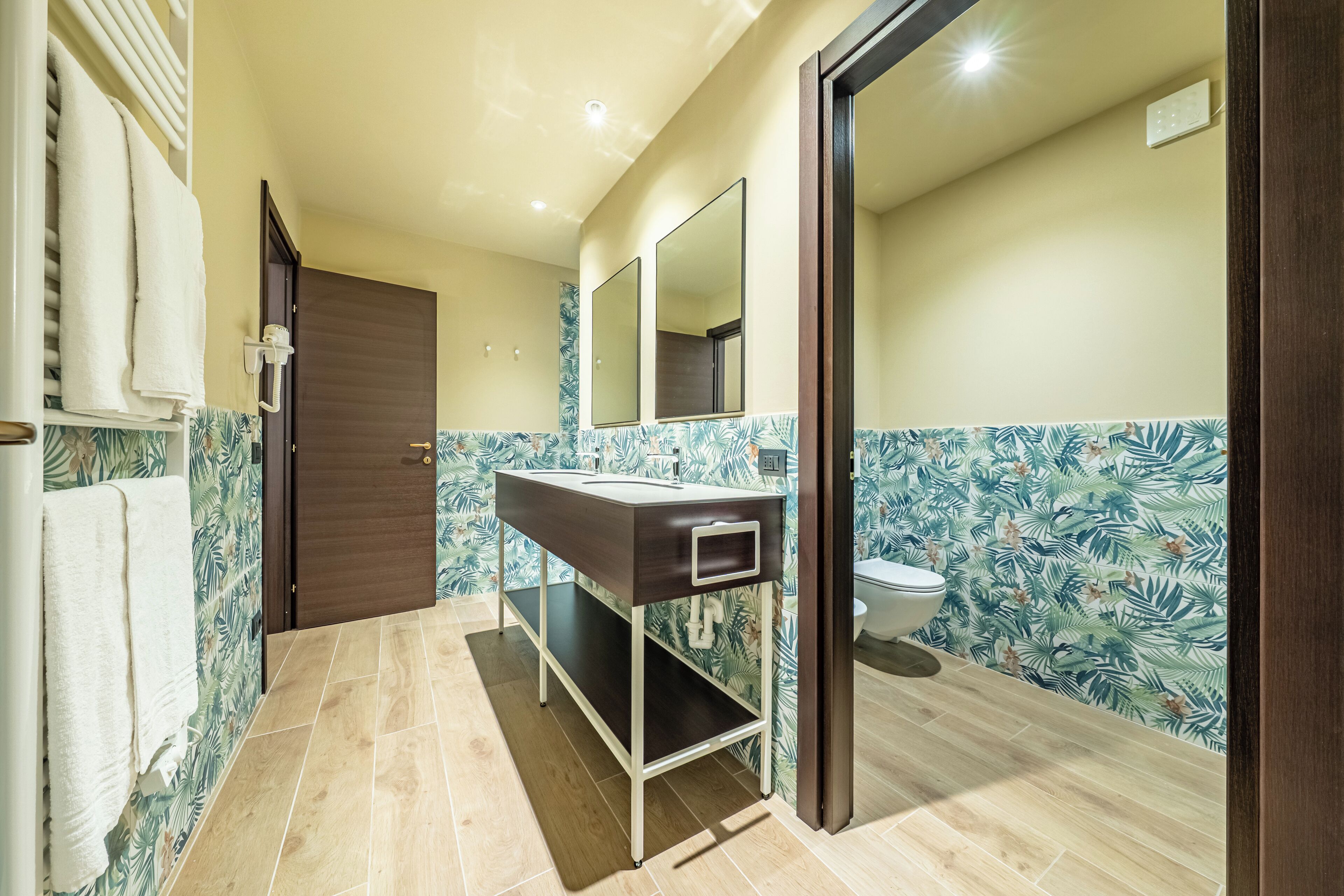 A bathroom with a wooden vanity, a toilet, and a shower area.